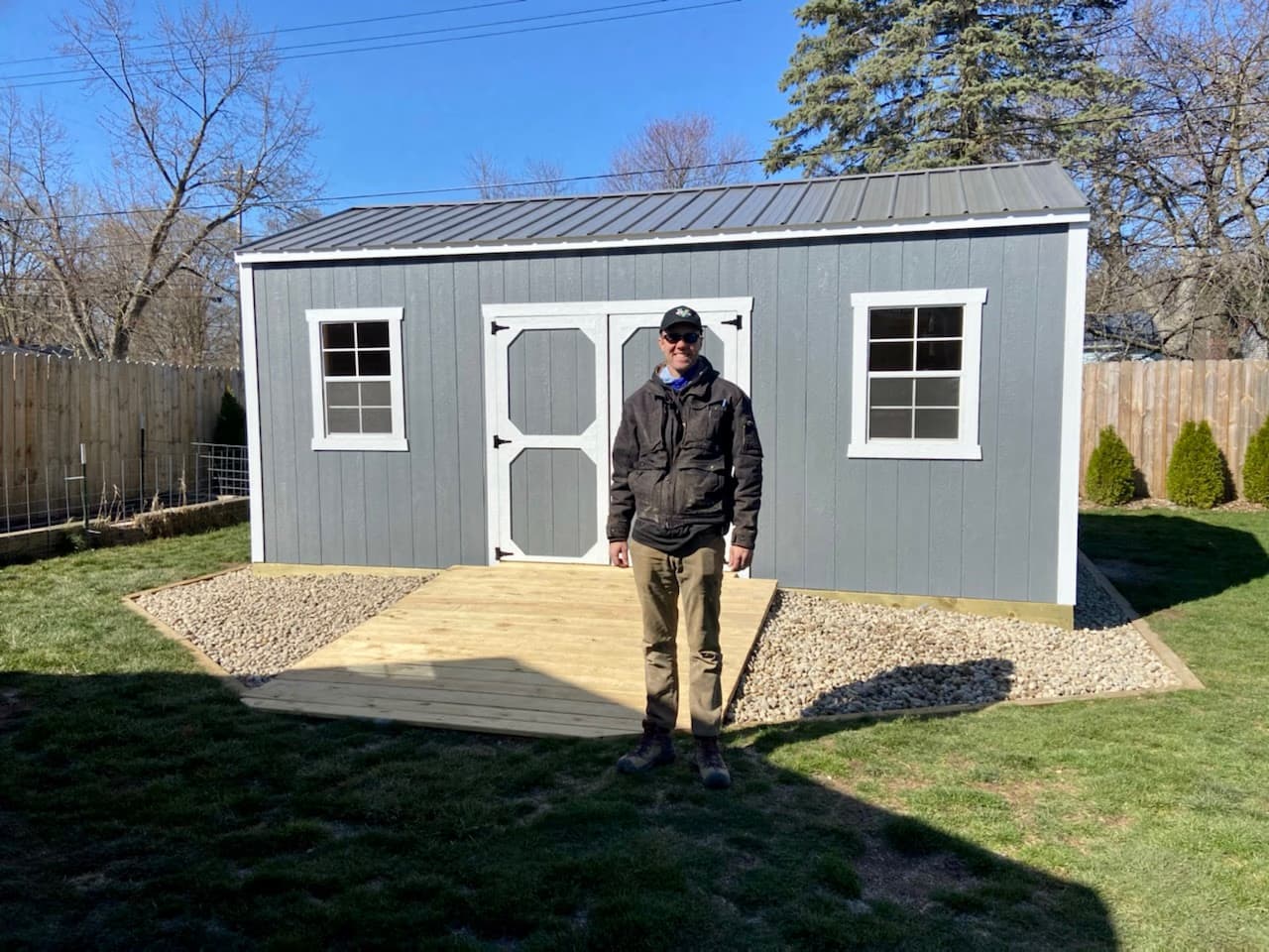 Amish Outdoor Buildings customer in his Southern Michigan backyard with a freshly delivered gray garden shed