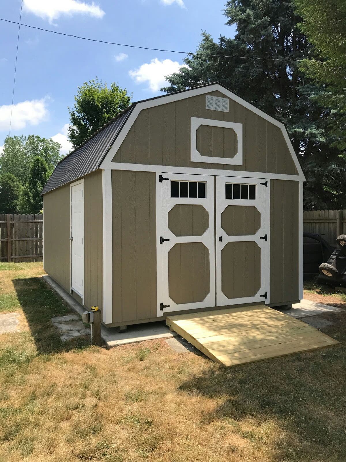 Tan lofted barn with white trim in customer backyard